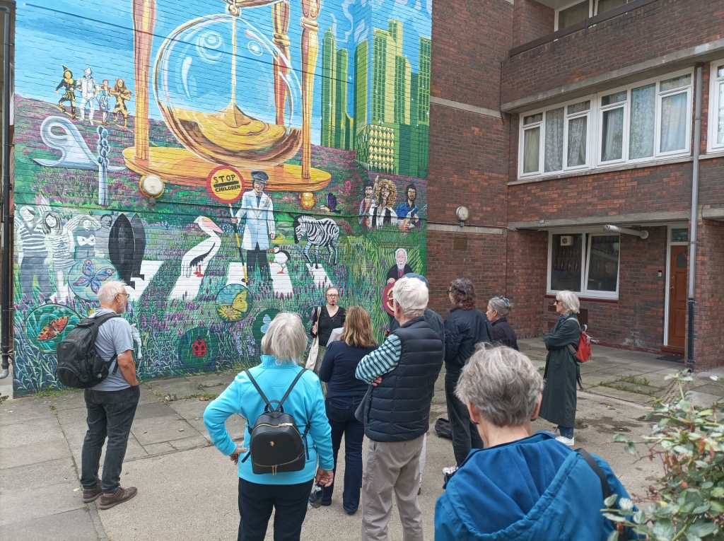 A group of people standing looking at a colourful mural